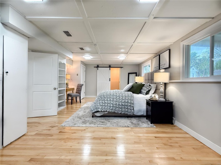 Bedroom with a barn door, multiple windows, light wood-style floors, baseboards, and visible vents