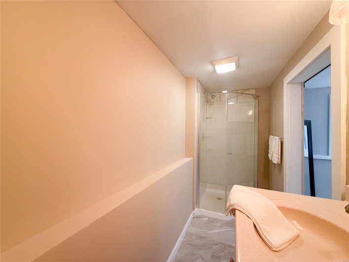 Bathroom featuring baseboards, marble finish floor, and a shower stall