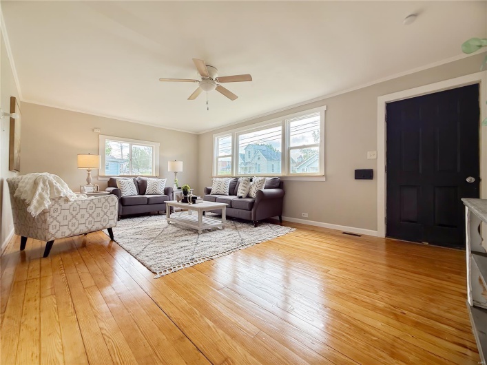 Living room with crown molding, ceiling fan, light wood finished floors, baseboards, and visible vents