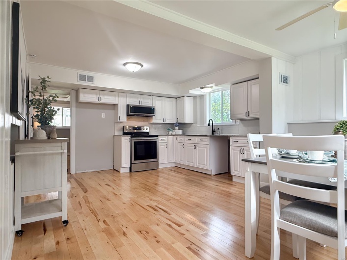 Kitchen with appliances with stainless steel finishes, ceiling fan, light wood-style flooring, and visible vents