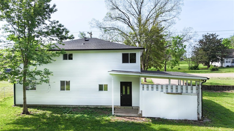 Back of property featuring a lawn and roof with shingles