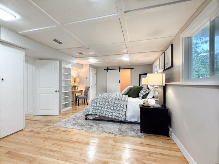 Bedroom featuring baseboards, visible vents, a barn door, and light wood-style flooring