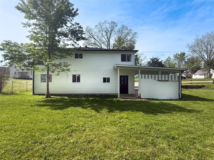 Back of property with a yard and fence