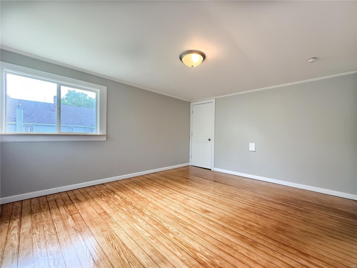 Spare room with crown molding, wood-type flooring, and baseboards