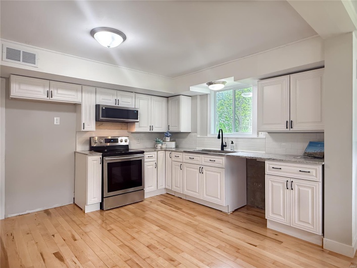 Kitchen with backsplash, visible vents, a sink, light wood-style floors, and stainless steel appliances