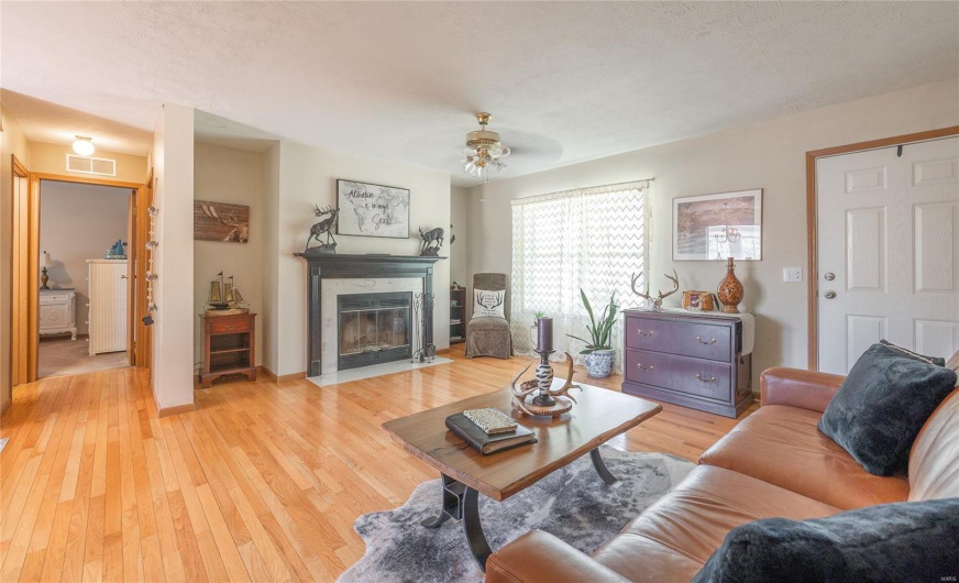 Living area featuring light wood-style floors, ceiling fan, washer / dryer, visible vents, and a high end fireplace