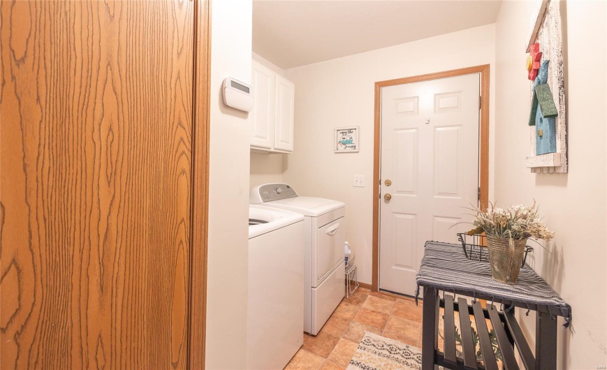 Laundry room with washer and dryer, cabinet space, and stone finish floor