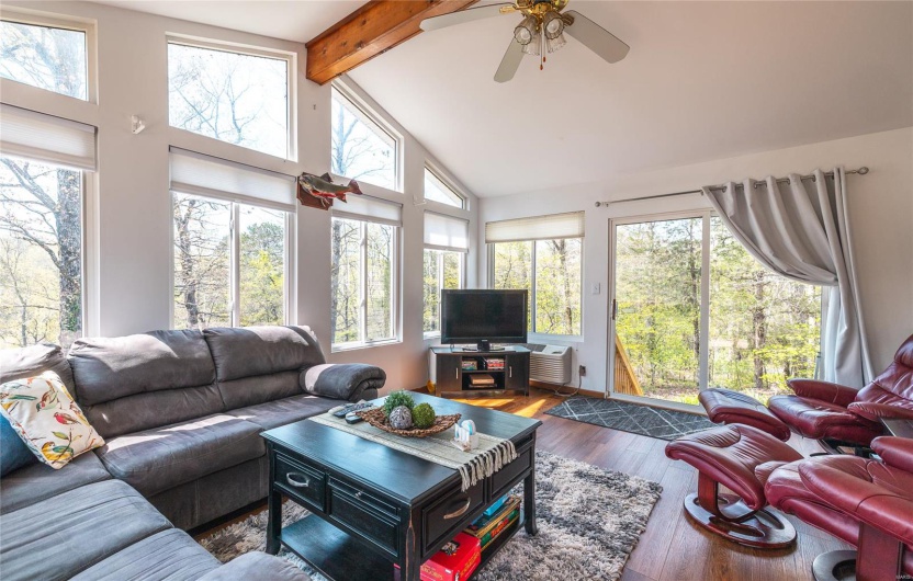 Living area with beam ceiling, wood finished floors, a ceiling fan, and high vaulted ceiling