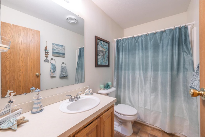 Bathroom featuring curtained shower, toilet, and vanity