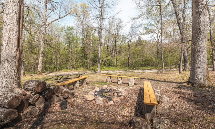 View of yard with an outdoor fire pit and a view of trees
