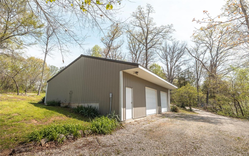 View of side of home featuring a garage and an outbuilding