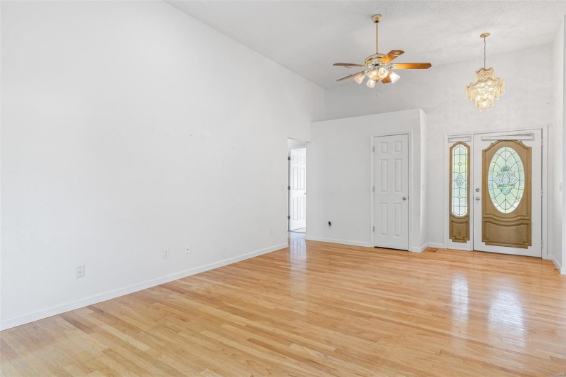 Foyer featuring high vaulted ceiling, baseboards, ceiling fan with notable chandelier, and light woo flooring