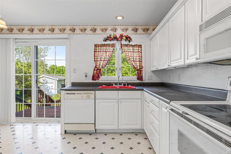 Kitchen featuring a sink, white cabinetry, dark countertops, and white appliances