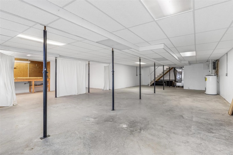 Partially finished basement featuring stairs and water heater
