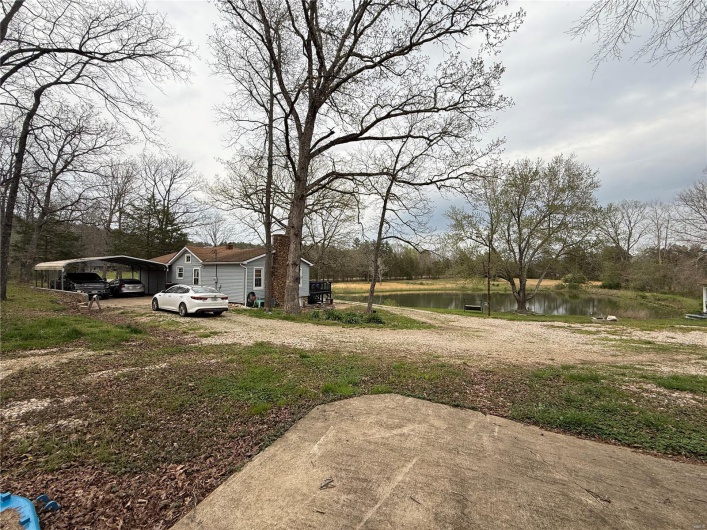View of yard with a carport, driveway, and a water view