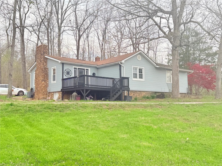View of front of home with a chimney, a front yard, and a wooden deck