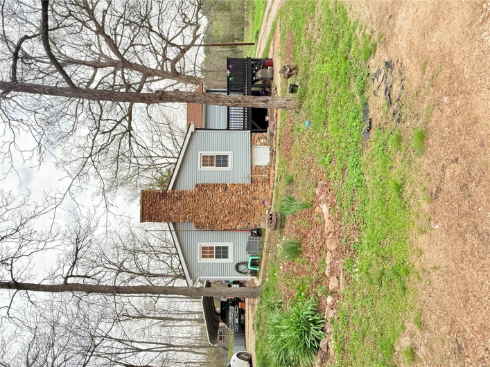 View of property exterior featuring a deck, a chimney, and a detached carport