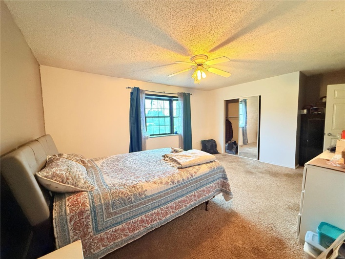 Bedroom with a textured ceiling, a ceiling fan, and carpet flooring