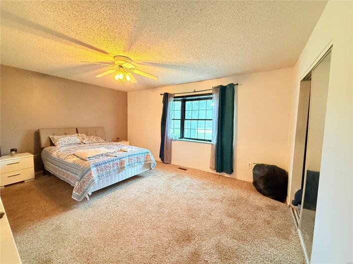 Bedroom featuring a ceiling fan, a textured ceiling, a closet, and carpet flooring
