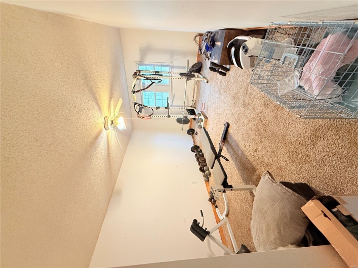 Workout room featuring a textured ceiling, ceiling fan, baseboards, and carpet floors