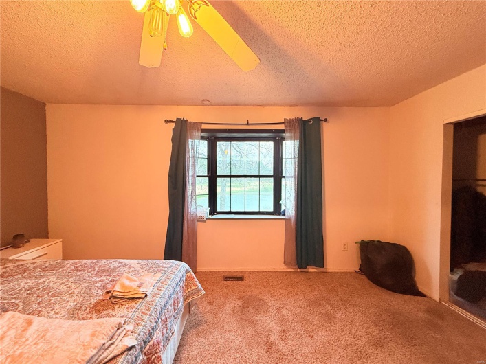 Bedroom featuring a textured ceiling, ceiling fan, and carpet flooring