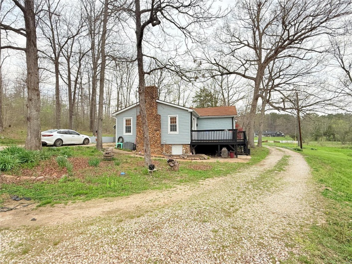 View of home's exterior with a deck, a chimney, and driveway