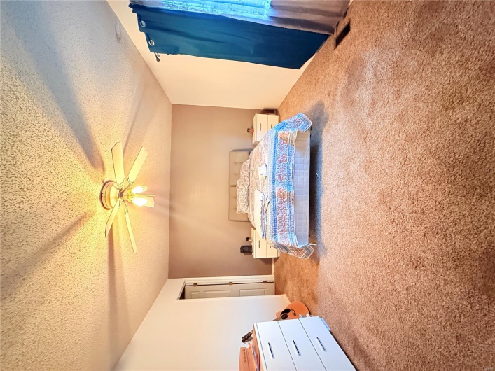 Carpeted bedroom with a textured ceiling, visible vents, and a ceiling fan
