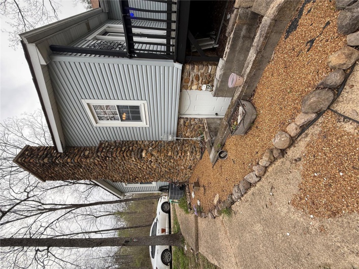 View of side of property with a deck, central air condition unit, and a chimney