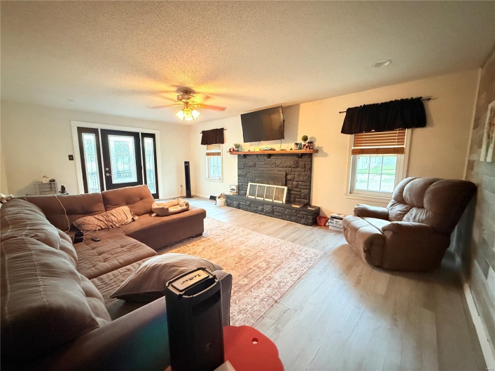 Living area with a textured ceiling, ceiling fan, wood finished floors, and a fireplace