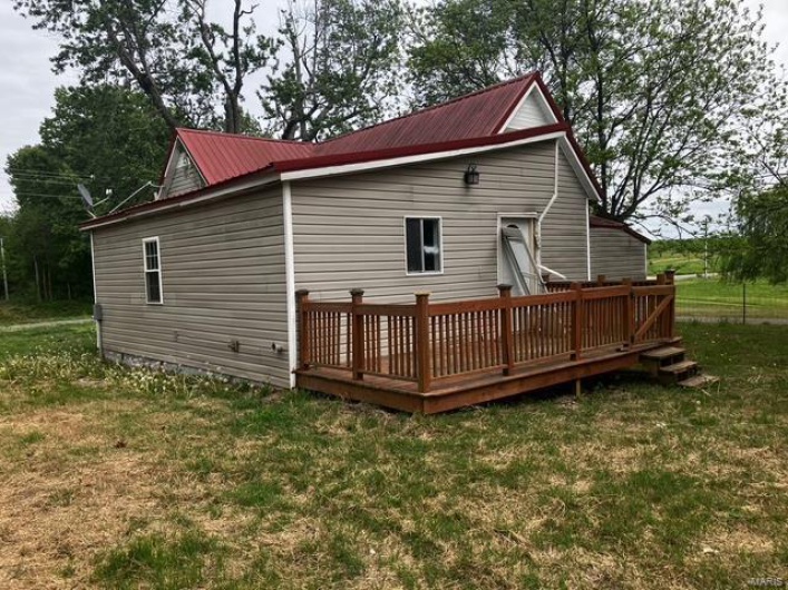 Back of house with a yard, a deck, and metal roof
