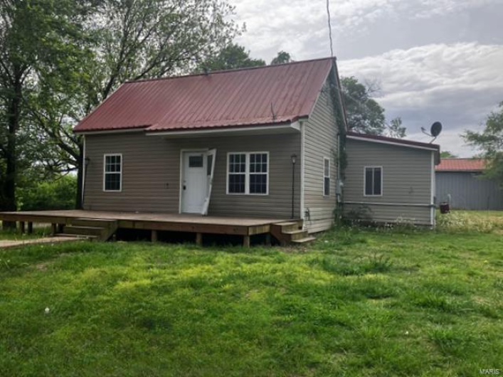 Side view of house with metal roof, a yard, and a deck