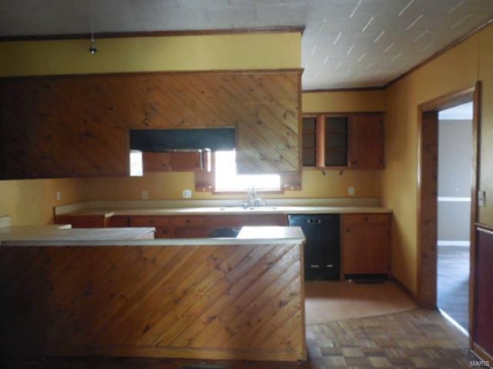Kitchen and dining area with brown cabinetry, a sink, dishwasher, and light countertops