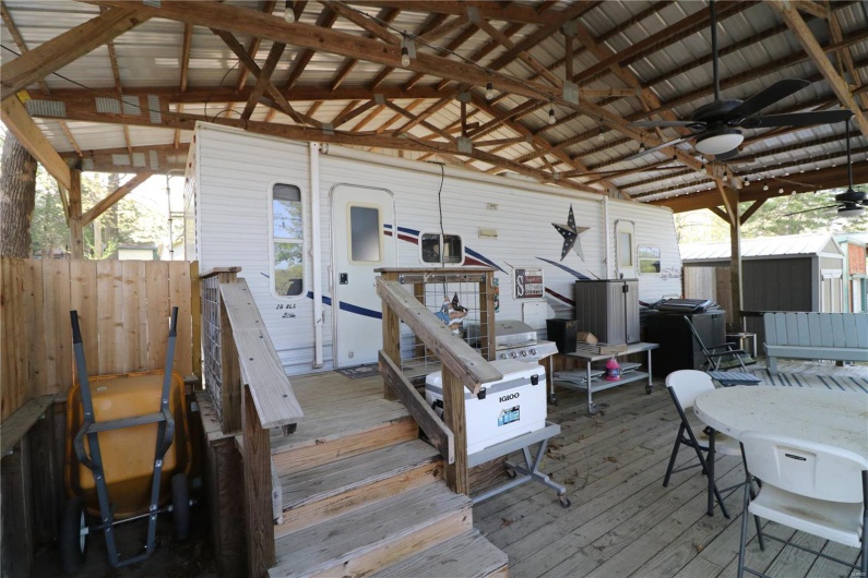 Deck with an outdoor structure, ceiling fan, fence, and a shed