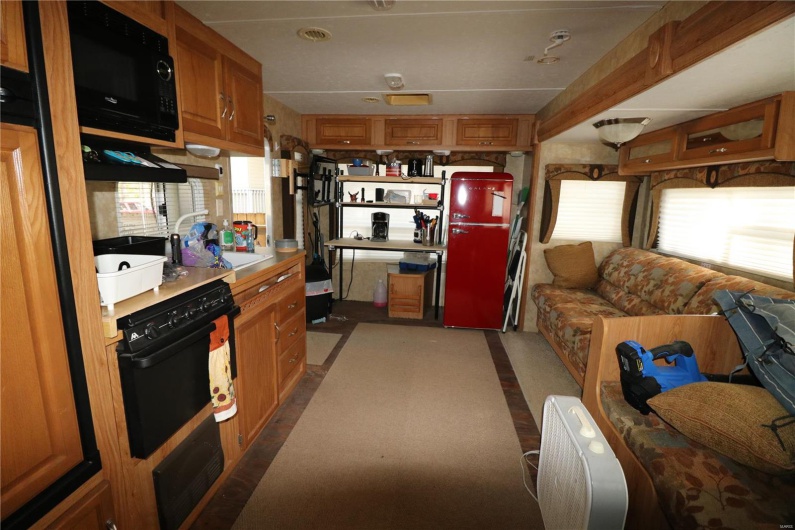 Kitchen featuring black microwave, light countertops, brown cabinetry, and a sink