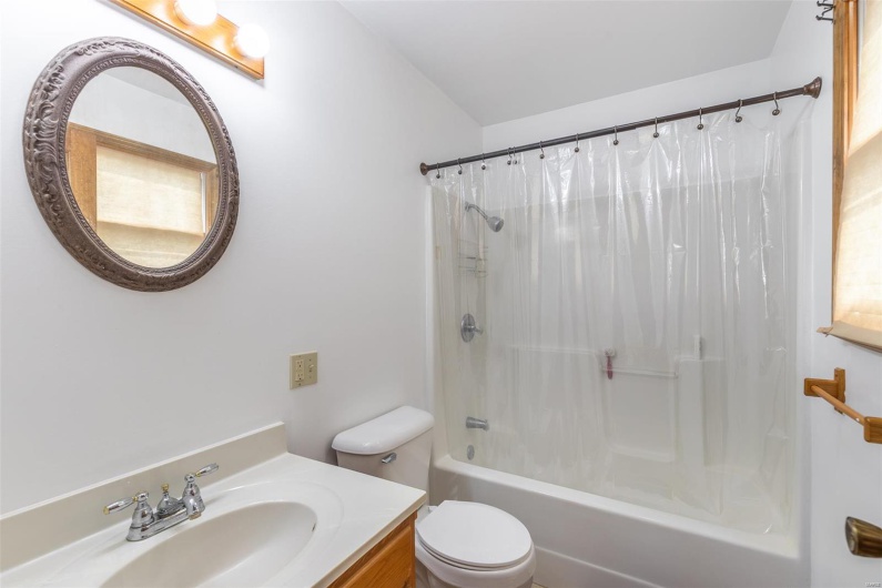 Bathroom featuring toilet, shower / bath combination with curtain, and vanity