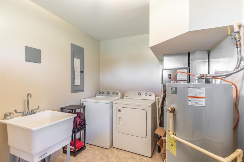 Washroom with gas water heater, independent washer and dryer, a sink, and electric panel