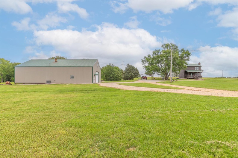View of grassy yard with driveway, an outdoor structure, and a pole building