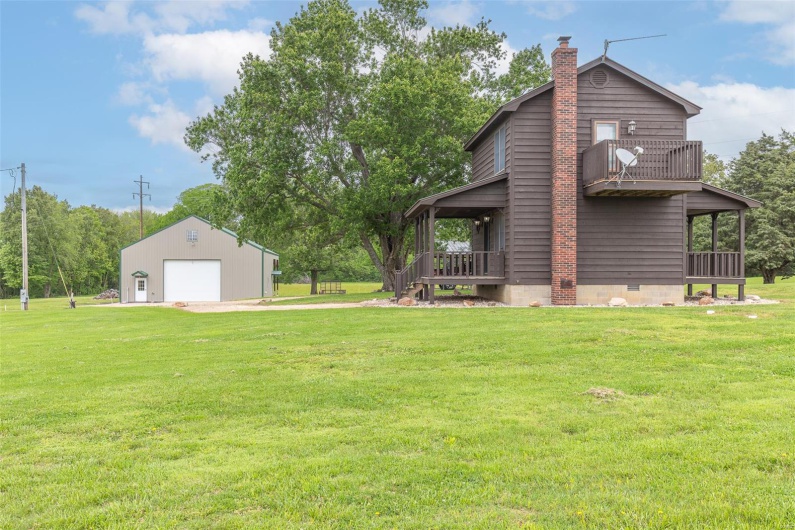 View of green lawn featuring a garage, driveway, and an outbuilding