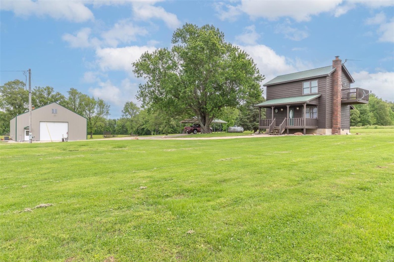 View of green lawn featuring a garage and covered porch