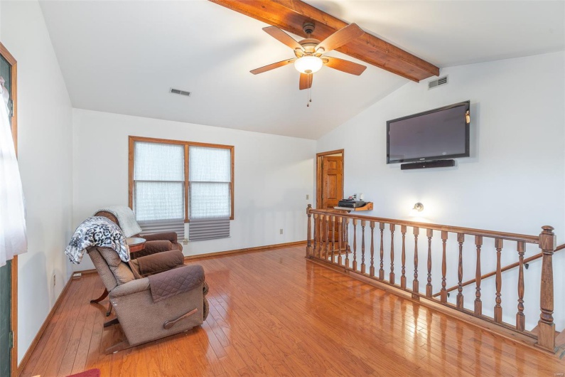 Sitting room with wood-type flooring, an upstairs landing, a ceiling fan, and baseboards