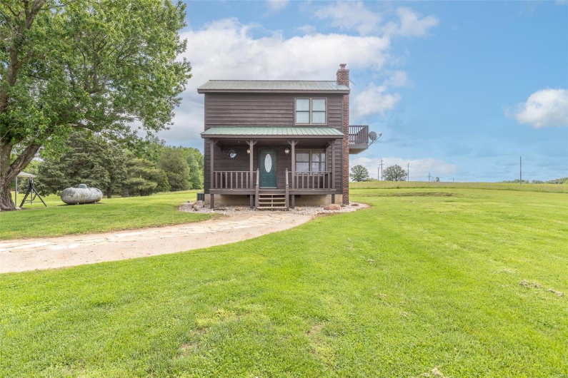 View of front of house featuring a chimney, a porch, a front yard, and metal roof