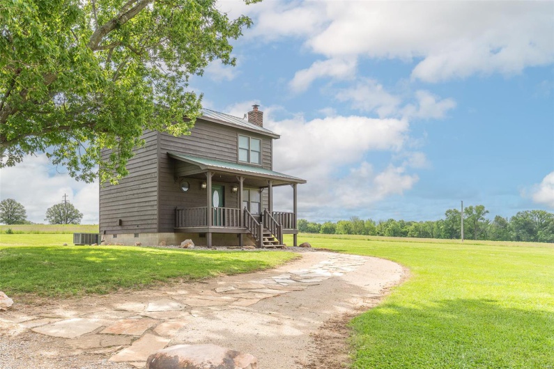 View of front of property with a porch, a chimney, a front lawn, and metal roof