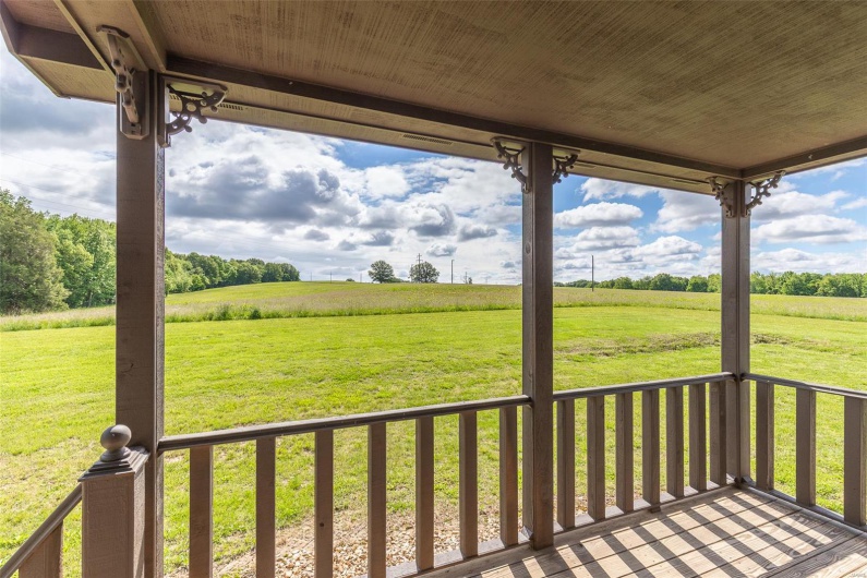Wooden terrace featuring a view of countryside and a yard