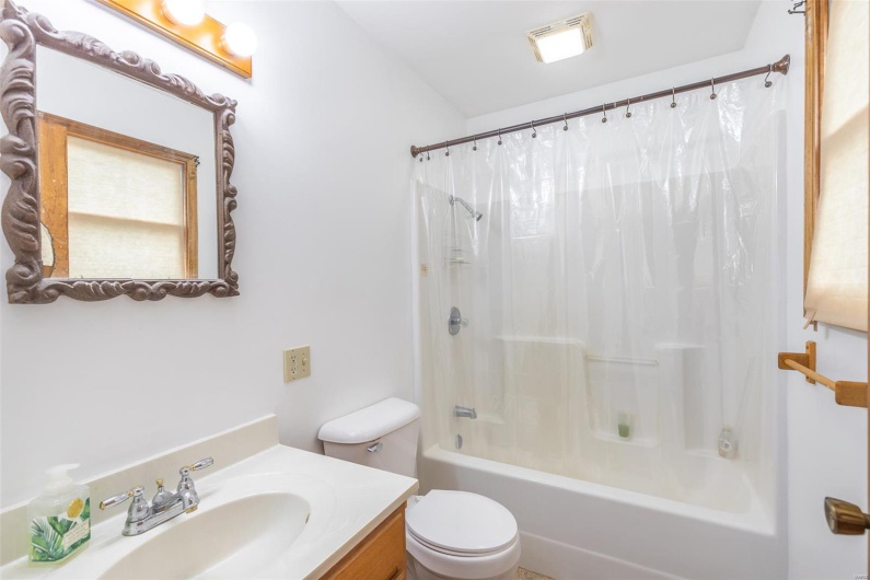 Bathroom with toilet, shower / tub combo with curtain, and vanity