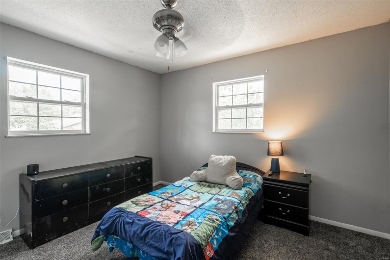 Bedroom with ceiling fan, a textured ceiling, visible vents, baseboards, and carpet