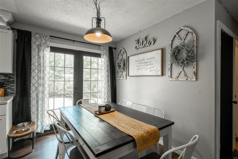 Dining space with french doors, a textured ceiling, and dark wood-type flooring