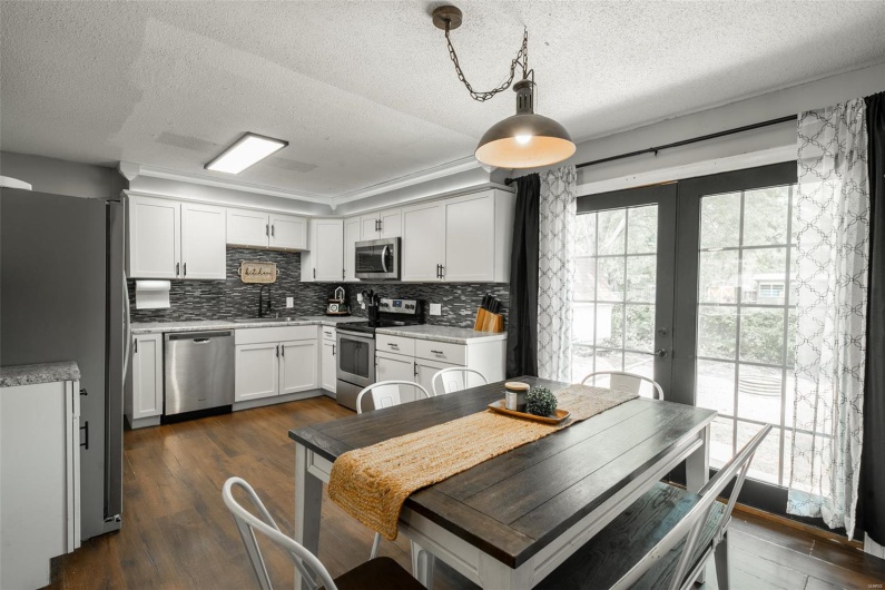 Kitchen featuring decorative backsplash, french doors, a textured ceiling, a sink, and stainless steel appliances