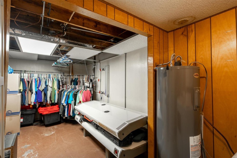 Basement with a textured ceiling and electric water heater