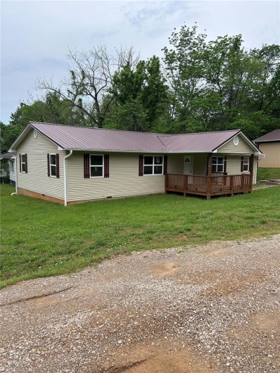 Single story home with a front yard and metal roof