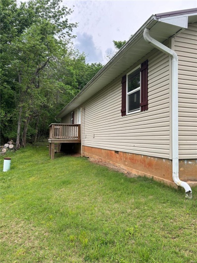 View of side of home featuring a lawn, crawl space, and a wooden deck
